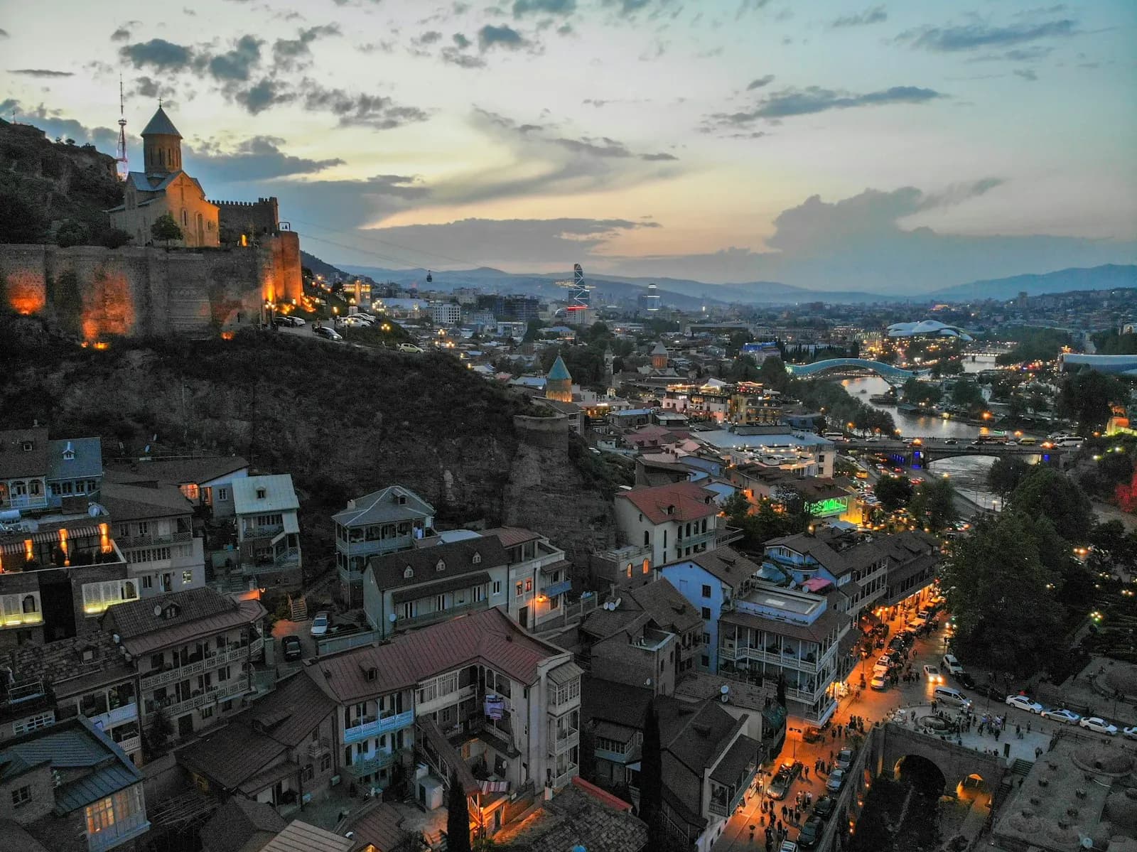 Tbilisi at dusk: the old town and the river, with the Narikala fortress lit up on the hill.